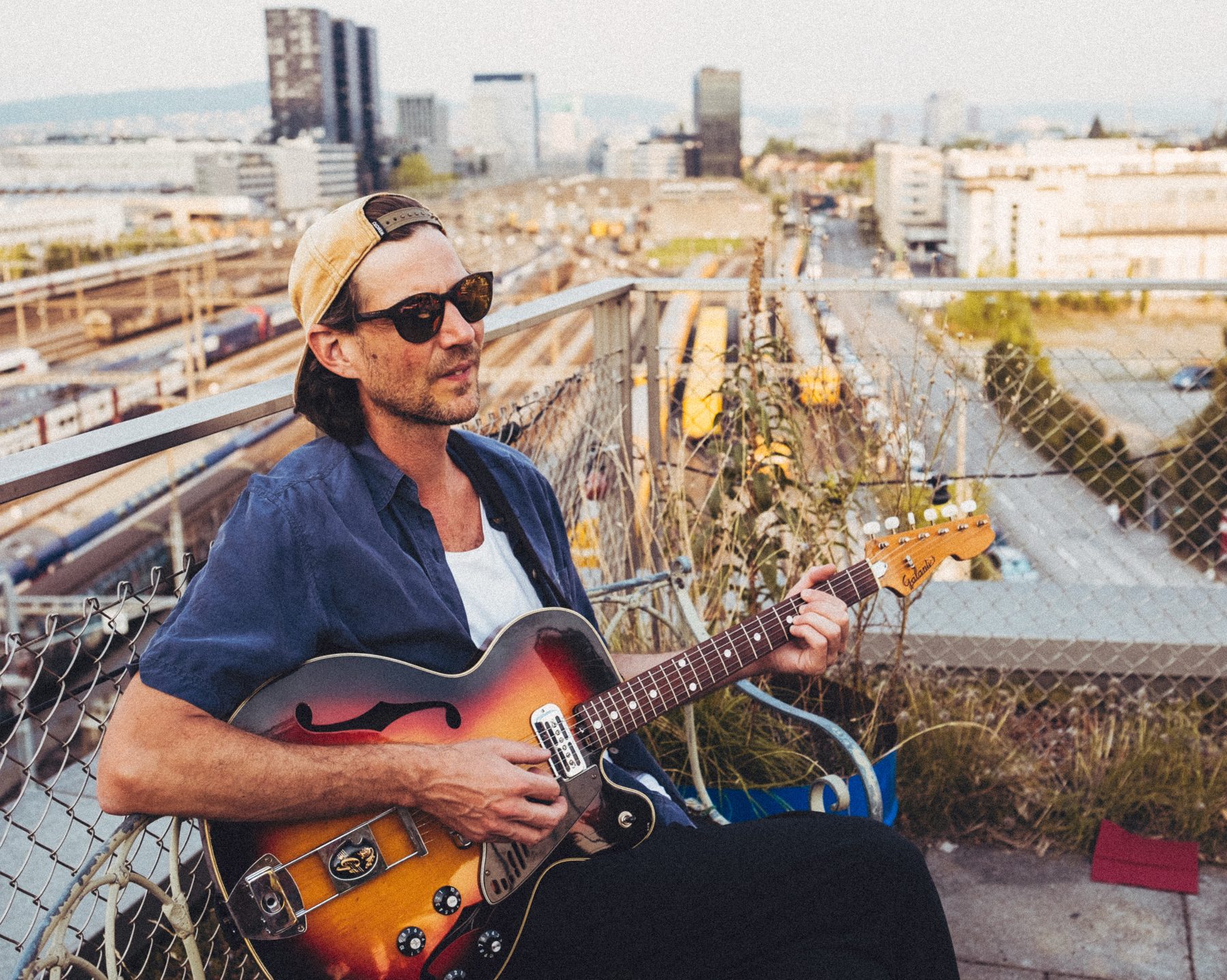 Florian Egli with a hollow-body guitar on a rooftop